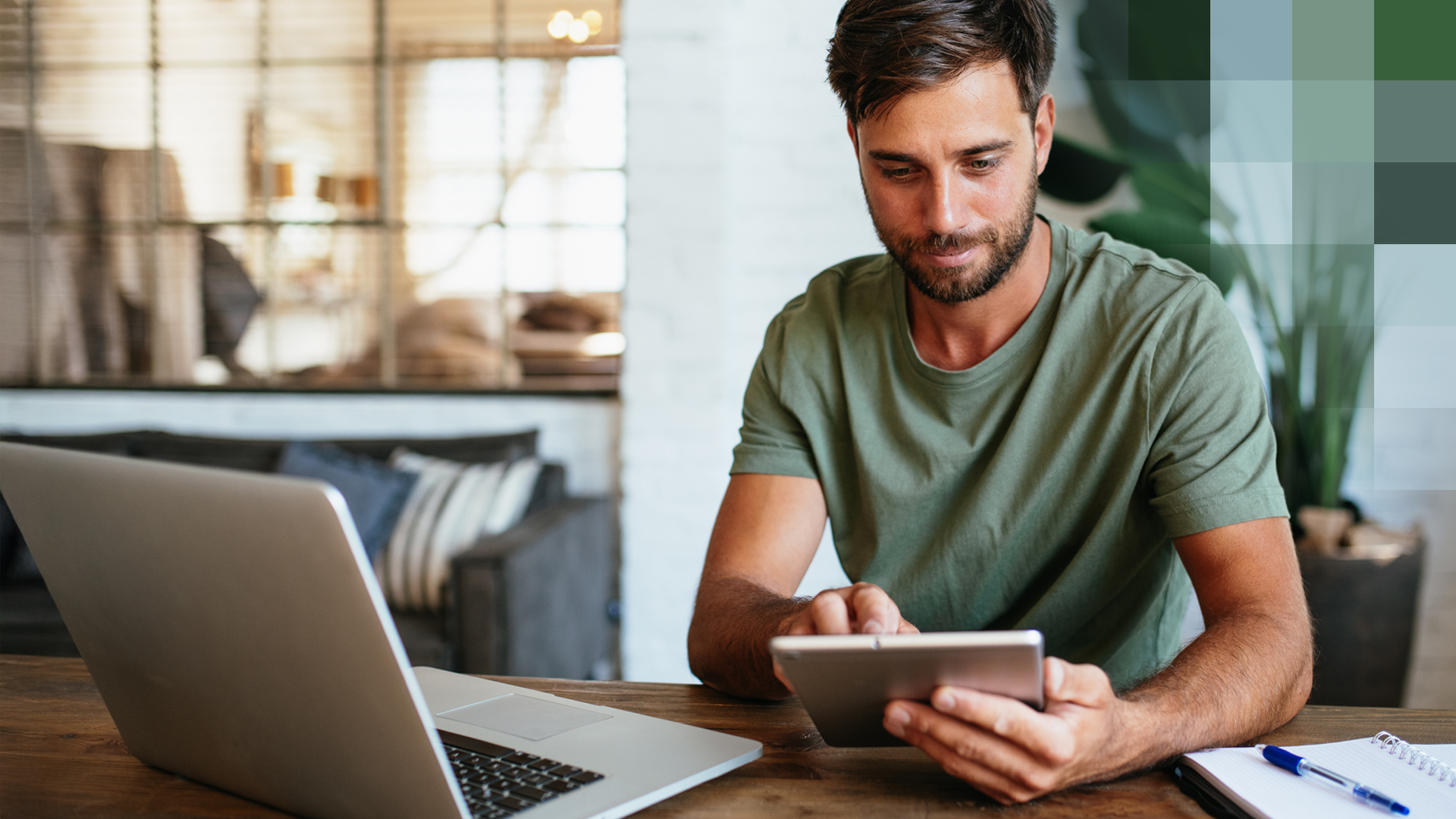 Un homme est assis à une table avec un ordinateur portable et une tablette et s’informe sur le libre choix du médecin.